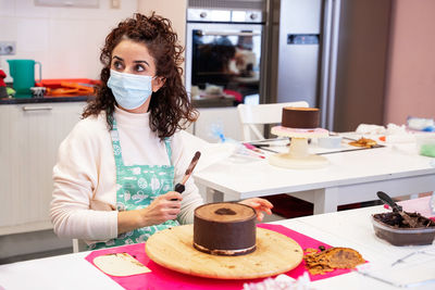 Portrait of young woman with cake on table