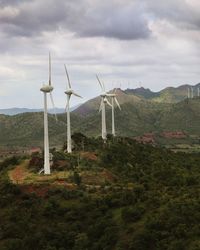 Wind turbines on field against sky