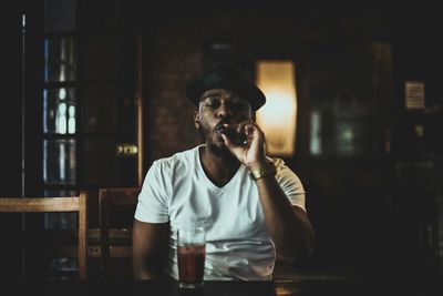 Young man smoking cigar while sitting on table at bar