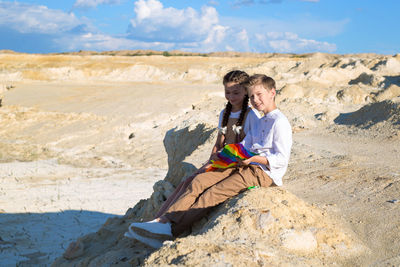 A boy and a girl collect kite sitting on a stone on a sunny summer day.