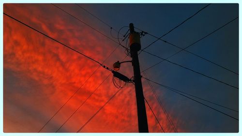 Low angle view of electricity pylon against sky during sunset