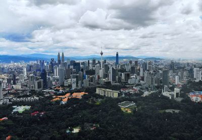 Aerial view of city buildings against cloudy sky