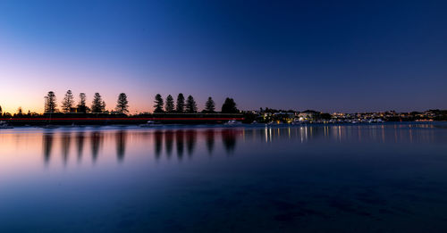 Reflection of trees in lake at sunset