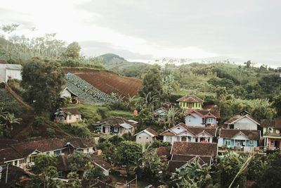 Houses by trees against sky