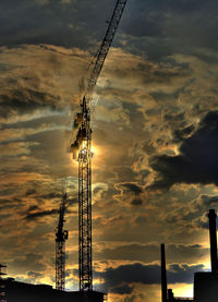 Low angle view of electricity pylon against cloudy sky