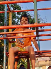 Full length of boy sitting on slide at playground