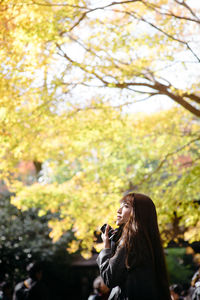 Young woman against tree