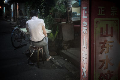 Rear view of man sitting on chair in city