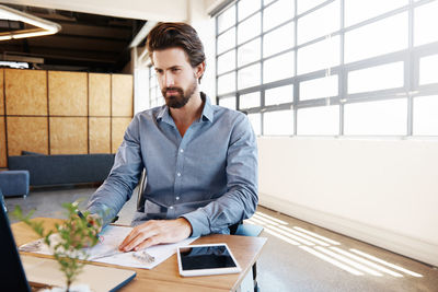 Young man using mobile phone while sitting on table