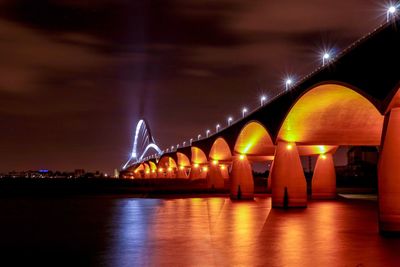 Illuminated bridge against sky at night