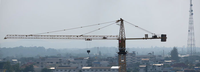 Cranes and buildings against sky