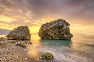 Scenic view of rocky beach against dramatic sky