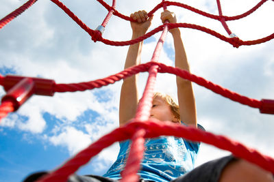 Low angle view of girl on rope against sky