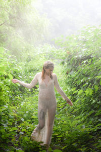 Woman standing by tree in forest