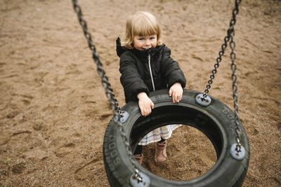 Portrait of playful girl pulling tire swing in park