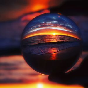 Close-up of crystal ball on glass against sky during sunset