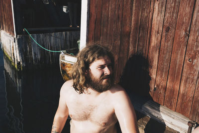 High angle view of shirtless man standing at lake by chalet