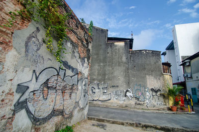 Graffiti on wall by building against sky