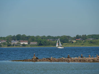 Sailboats in sea against clear sky