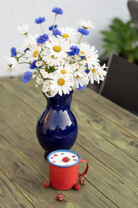 Fresh strawberry with cold milk in red mug on wild flowers background,childhood nostalgia