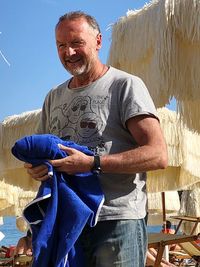 Portrait of smiling man standing against blue sky