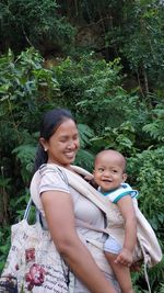 Mother carrying son while standing by plants