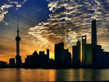 Silhouette of skyscrapers against cloudy sky
