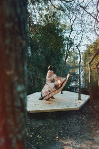 Woman wearing shawl while spinning in forest