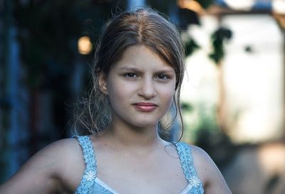 Close-up portrait of young woman standing at yard