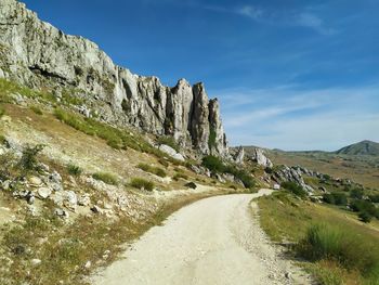 Road leading towards mountains against sky