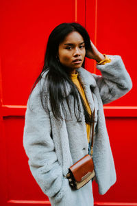 Portrait of beautiful woman standing against red wall