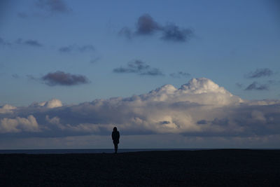 Silhouette man standing by sea against sky at dusk