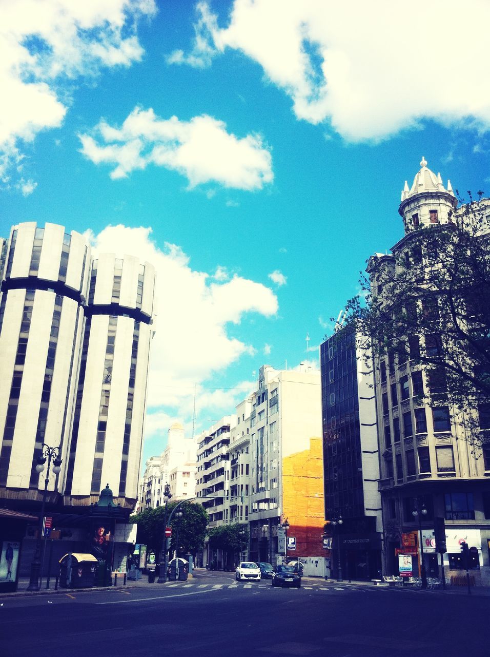 building exterior, architecture, built structure, city, sky, tall - high, tower, skyscraper, car, low angle view, cloud - sky, office building, transportation, modern, land vehicle, street, building, mode of transport, road, city life