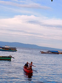 Rear view of man rowing boat in sea against sky