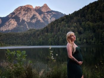 Woman standing by lake against mountains