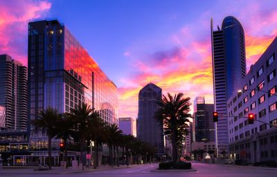 Modern buildings in city against sky at sunset