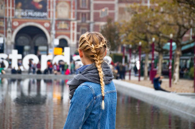 Rear view of woman with braided hair while standing in city