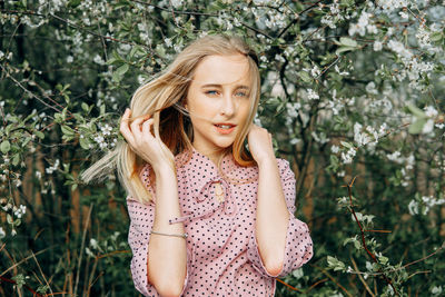 Blonde girl on a spring walk in the garden with cherry blossoms. female portrait, close-up. 