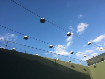 Low angle view of light bulbs hanging against sky