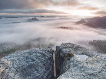 Broken rocks and crags in the nature park in saxony. misty vewpoint with hill and peak in distance