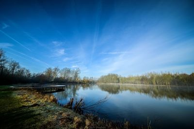 Reflection of trees in lake against blue sky