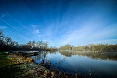 Reflection of trees in lake against blue sky