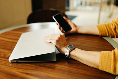 Midsection of man using mobile phone on table