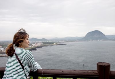 Rear view of woman standing over sea against sky