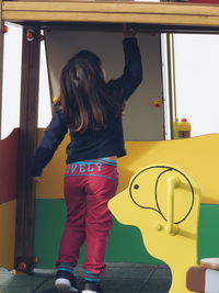 Rear view of girl standing by play equipment