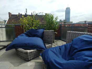 Low section of man relaxing by building against sky