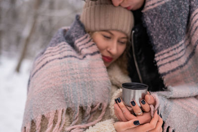 Couple holding coffee cup while embracing outdoors