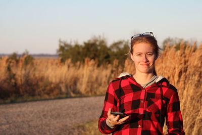 Young woman standing on field against sky during sunset