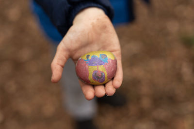 Close-up of boy holding a painted pebble