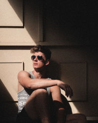 Young man wearing sunglasses sitting at home